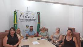 #DescriçãodaImagem todos sentados ao redor da mesa de reuniões, ao fundo o banner da FADERS Acessibilidade e Inclusão.